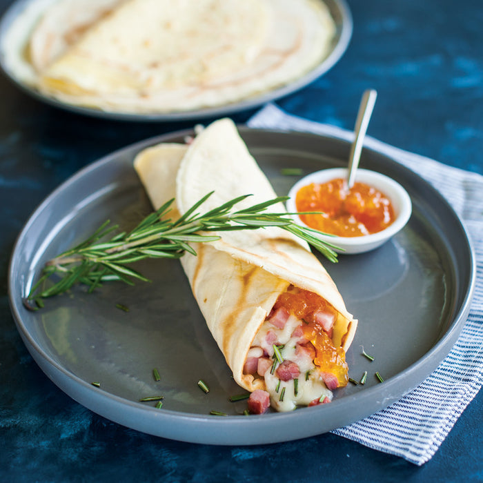 Savory ham and cheese crepe on a white plate