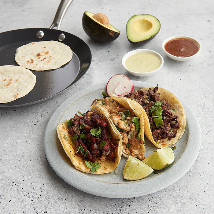 Crepe pan with a golden crepe next to plated tacos