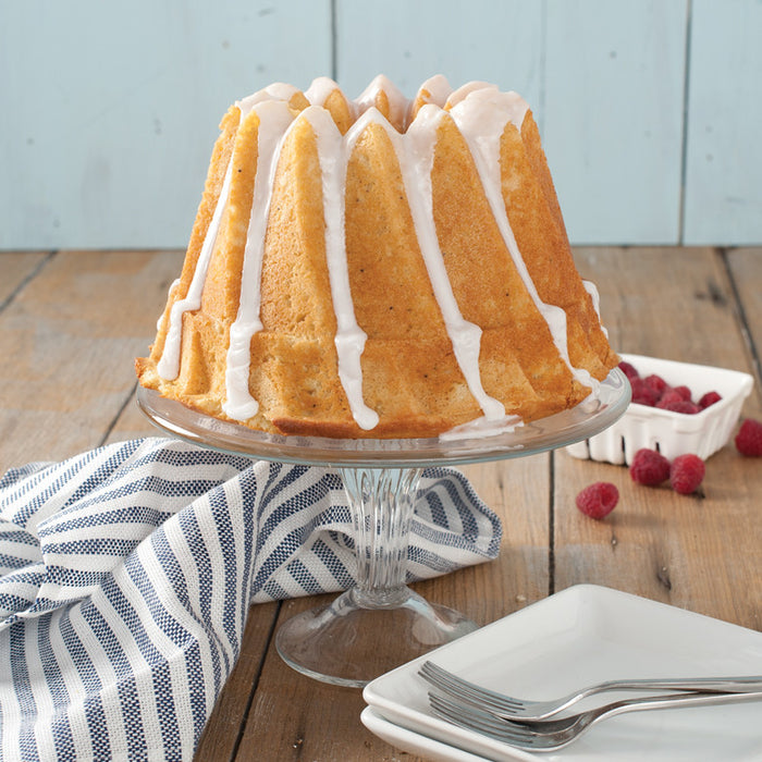 Glazed Kugelhopf Bundt cake on a glass cake stand with fresh raspberries