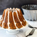 Glazed carrot Bundt cake with the Kugelhopf pan behind it