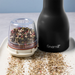 FinaMill Pepper Pod filled with mixed peppercorns beside a FinaMill mill and fresh cracked pepper