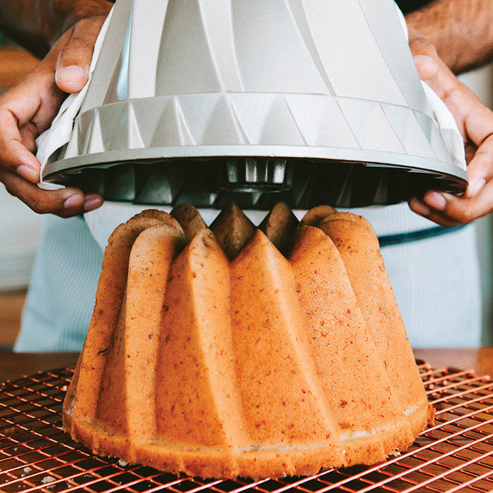 Lifting the Kugelhopf Bundt pan off a golden baked cake