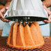 Lifting the Kugelhopf Bundt pan off a golden baked cake
